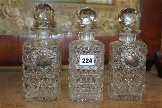 Three glass decanters and two silver labels